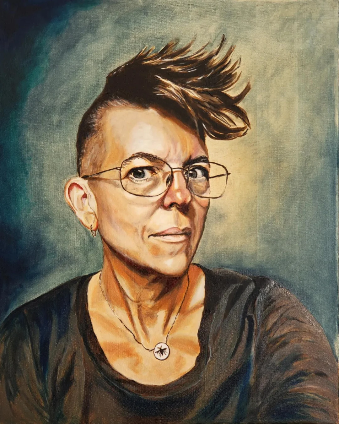 The image depicts a person with short hair named Corey and a mohawk brushed to the right side of their head. They are wearing glasses, which have a thin frame. The person is dressed in a dark shirt. Around their neck, they are wearing a necklace that features a circular pendant. The background of the image is a blue/green gradient. The person's gaze is directed straight at the camera. There is no text present in the image.